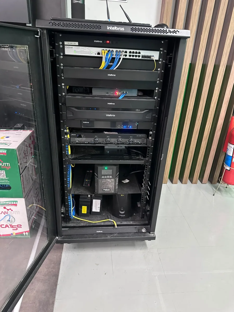Rack de CFTV instalado pela MAGE Service, com switch PoE identificado por etiqueta de IP, cabeamento separado por cor, gravador e nobreak.
